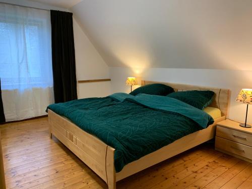 a bedroom with a bed with a green comforter and two lamps at Ferienwohnung Varus in Ostercappeln