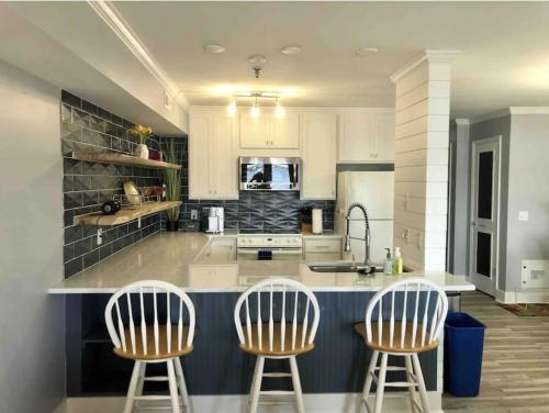a kitchen with three bar stools and a counter top at Newly Renovated Beach Condo with STUNNING Water Views! Monthly and Weekly Specials! in Carolina Beach