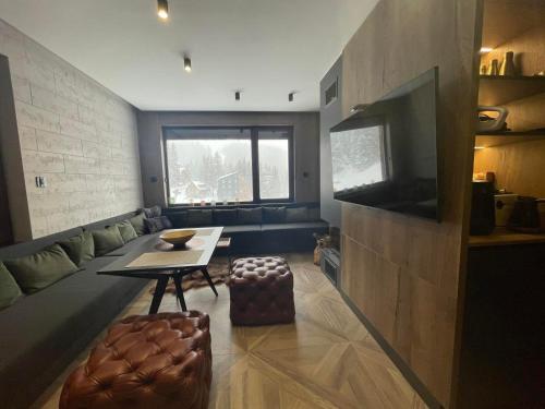 Una sala de estar con una mesa y un televisor. en Stella Bianca Apartman, en Jahorina