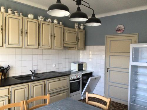 une cuisine avec des armoires en bois et un four à plaques de cuisson dans l'établissement Les Glycines, à Vic-sur-Cère