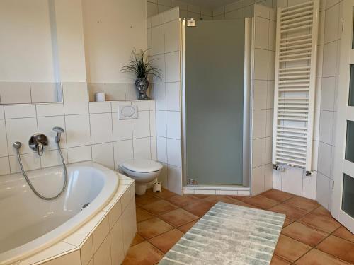 a bathroom with a tub and a toilet and a shower at Ferienwohnung Varus in Ostercappeln