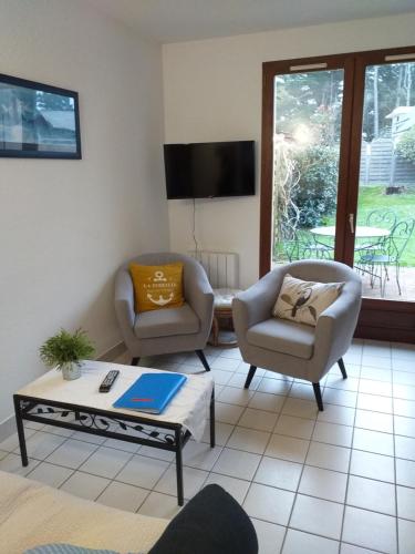 sala de estar con 2 sillas y mesa de centro en Maison, 2 chambres, 400m de la plage., en La Turballe