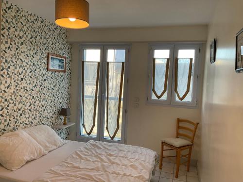 - une chambre avec un lit, 2 fenêtres et une chaise dans l'établissement Appartement centre ville près du port avec parking et wifi, à La Rochelle
