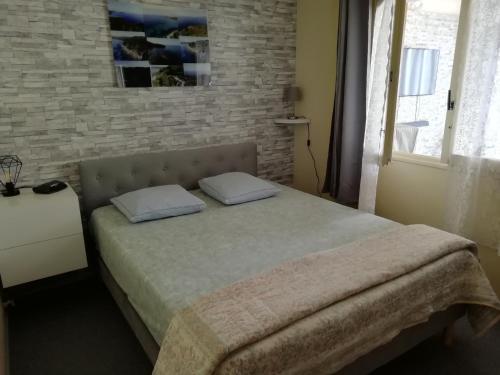 une chambre avec un lit avec un mur de briques dans l'établissement Appartement classé 3 étoiles au 1er étage d'une maison avec jardin dans un quartier calme, à Cavalaire-sur-Mer