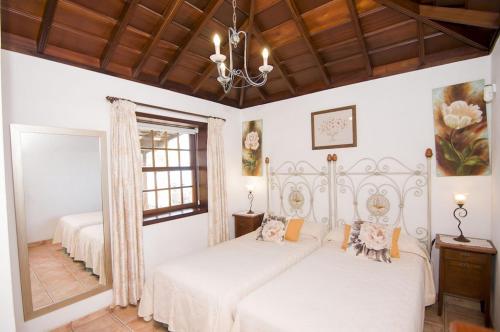 a white bedroom with two beds and a chandelier at Casa Los Mangos in Fuencaliente de la Palma