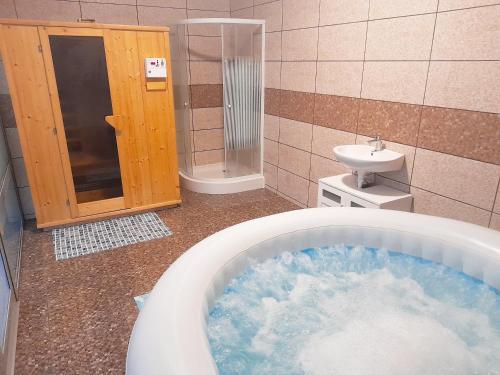 a bathroom with a tub of water and a sink at Mátra Wellness Vendégház in Parádsasvár