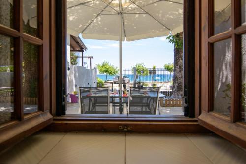 een open raam met uitzicht op een tafel met een paraplu bij Summer House by the Sea in Chorefto