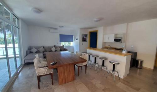 Miami Inn في نويفو فايارتا: مطبخ وغرفة معيشة مع طاولة وكراسي خشبية