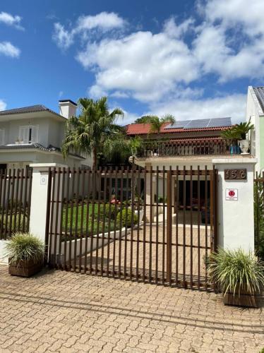 a gate in front of a house with palm trees at Suíte aconchegante in Santa Cruz do Sul