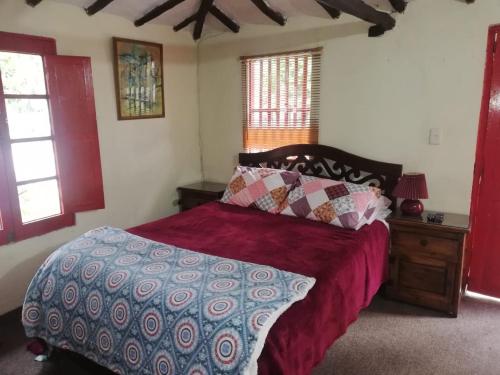 a bedroom with a bed with a red comforter at Hotel y Centro de Convenciones Pueblito de Yerbabuena Paraíso Natural in Chía