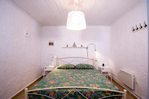 een kleine slaapkamer met een bed met een groene deken bij Summer House by the Sea in Chorefto