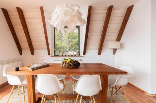 a dining room with a wooden table and white chairs at Vista Mountain House in Kopaonik