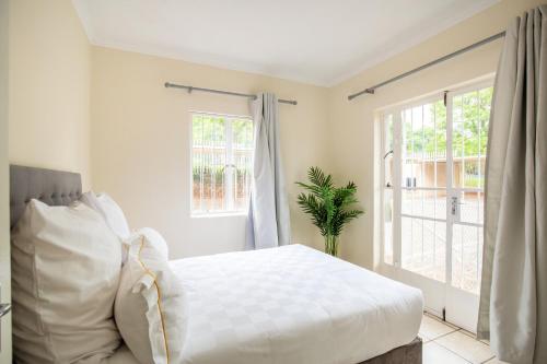 a white bedroom with a bed and a window at Beautiful Two Bedroom Appartment In Hatfield in Pretoria