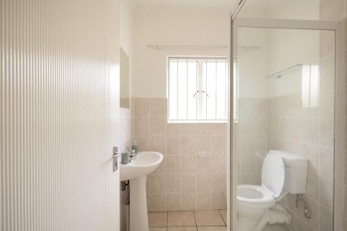 La salle de bains blanche est pourvue de toilettes et d'un lavabo. dans l'établissement Beautiful Two Bedroom Appartment In Hatfield, à Pretoria