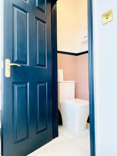 a bathroom with a blue door and a toilet at Duke and Duchess Apartments and Rooms - Private in Room Hot Tub Suites in London