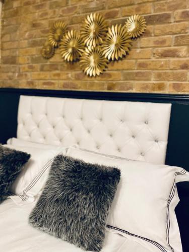 a bed with black and white pillows and a brick wall at Duke and Duchess Apartments and Rooms - Private in Room Hot Tub Suites in London