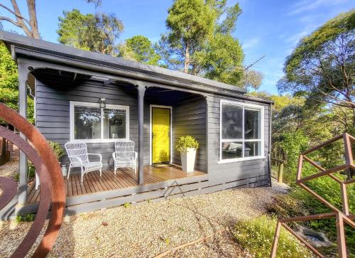 a tiny house with a deck with two chairs at Aurora Cottage in Hepburn Springs