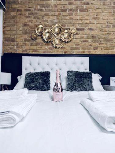 a bedroom with a white bed with a bottle on it at Duke and Duchess Apartments and Rooms - Private in Room Hot Tub Suites in London