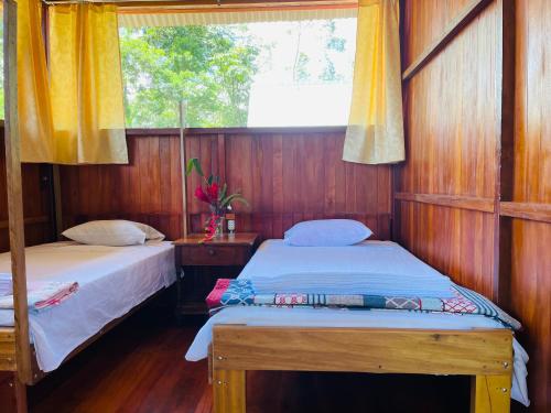 two beds in a room with a window at Sunrise of Tambopata in Puerto Maldonado