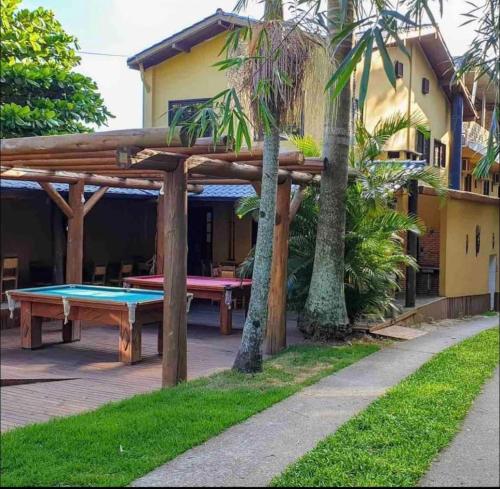 a patio with a ping pong table and a wooden pergola at Joaquina Guest House in Florianópolis