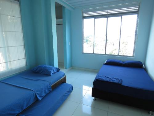 a blue room with two beds and a window at Nirvana Casa de Huéspedes in Melgar