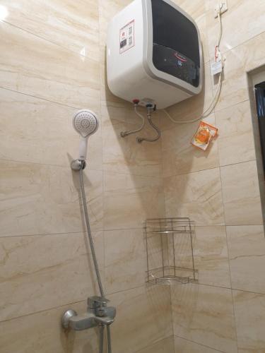 a bathroom with a shower with a tv on the wall at Guest House Omah Ningrat Bandung in Bandung