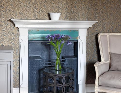 a vase of purple flowers on a table next to a fireplace at No33 HUNSTANTON BOUTIQUE ROOMS in Hunstanton