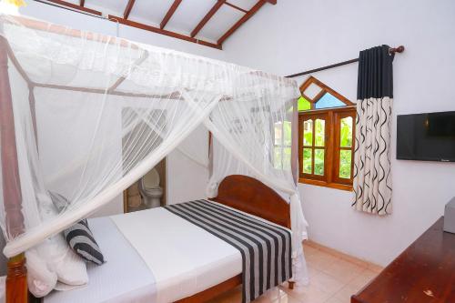 a bedroom with a bed with a mosquito net at Green Villa Apartment in Unawatuna