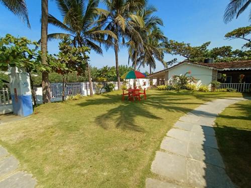 a yard with a table and a green umbrella at Anthy’s Guesthouse and Restaurant in Benaulim