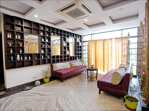 a living room with two purple couches and shelves at Hotel Indira Nikunj in Rishīkesh