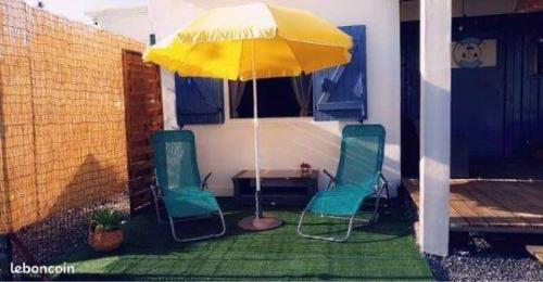 een patio met 2 stoelen en een parasol bij Ti Caz Laleu in Saint-Leu