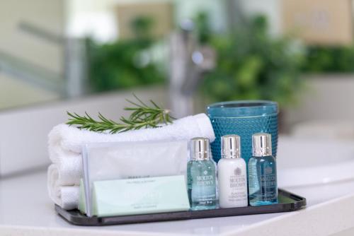 a tray with four bottles of soap and towels at Rhyll Haven Luxury Getaway Apartments in Rhyll