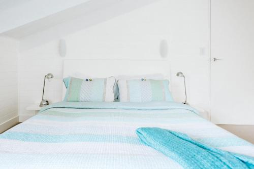 a bed with blue and white sheets and pillows at Rhyll Haven Luxury Getaway Apartments in Rhyll