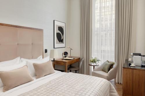 a bedroom with a bed and a desk and a chair at The Queens Gate Hotel in London