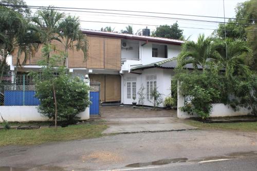 a white house with a blue door and trees at The Sisara in Kataragama