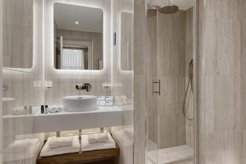 a white bathroom with a sink and a shower at The Queens Gate Hotel in London