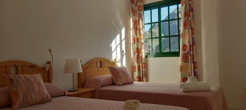 a bedroom with two beds and a window at Apartamentos Correhuela in Hermigua