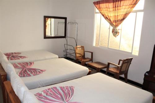 カタラガマにあるThe Sisaraのベッド3台と椅子、窓が備わる客室です。