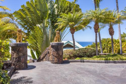 a pathway with palm trees and the ocean in the background at Waterfall House - Hawaii in Kailua-Kona