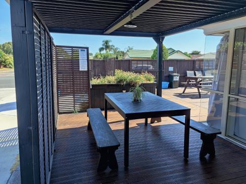un patio con una mesa y un banco en una terraza en Holiday Home in Papamoa, en Tauranga