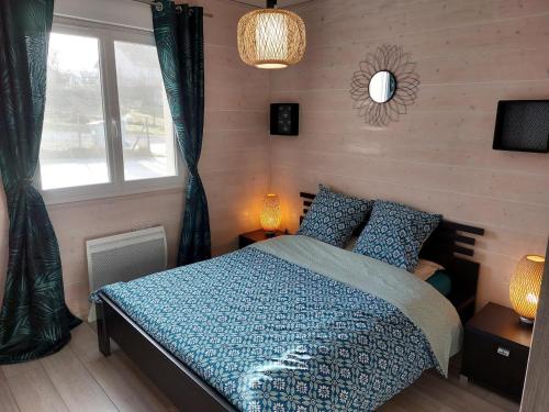 um quarto com uma cama com um edredão azul e uma janela em Entre Lacs Et Montagnes , Maison individuelle, lits préparés et ménage inclus em Barésia-sur-lʼAin