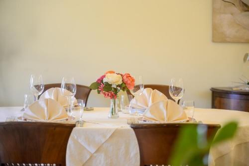a table with glasses and a vase of flowers on it at Hotel Al Poggio Verde in Barghe