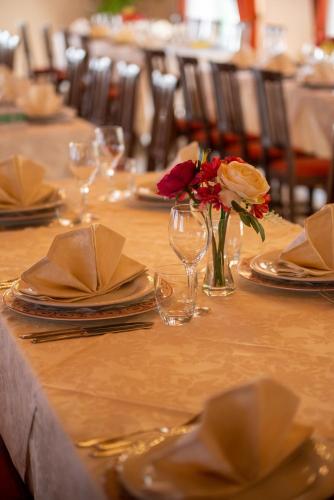 a table with plates and a vase with flowers on it at Hotel Al Poggio Verde in Barghe