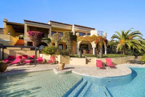 een huis met een zwembad en roze stoelen bij Villa-la-Sebastiane in Sainte-Maxime