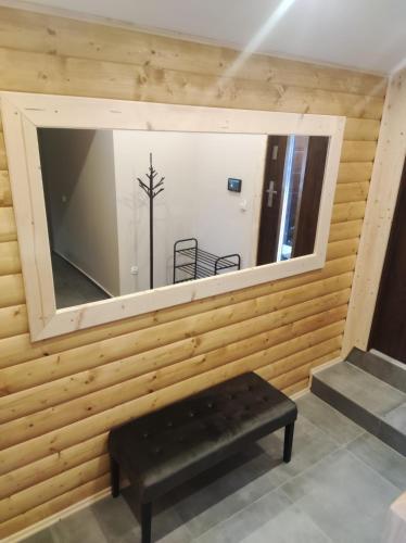 a mirror on a wall with a bench in a room at Gościnna Chata Domek in Jaworki