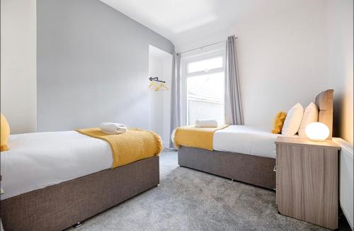 1 dormitorio con 2 camas y ventana en 4 Bed Executive Style House - Near City Centre en Swansea