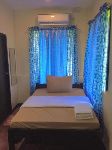 a bed in a room with blue curtains at The Family Farm Stay in Cauayan City
