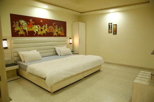 a bedroom with a large bed with a painting on the wall at Villa 21 Agra in Agra
