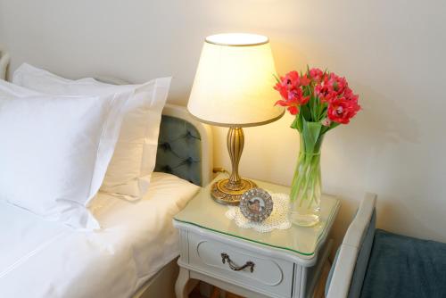 a table with a lamp and a vase of flowers on a bed at ApartHotel Vila Minka in Ljubljana