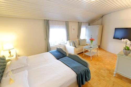 a bedroom with a white bed and a living room at ApartHotel Vila Minka in Ljubljana